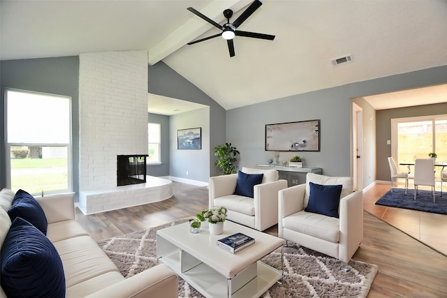 living room featuring plenty of natural light, visible vents, wood finished floors, and a ceiling fan