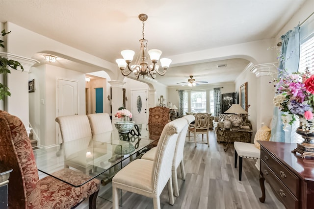 dining space featuring arched walkways, a chandelier, light wood finished floors, and ceiling fan