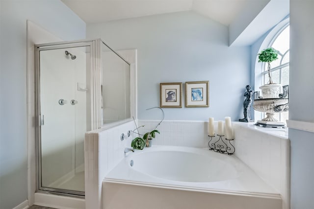 bathroom featuring a shower stall, a garden tub, and vaulted ceiling