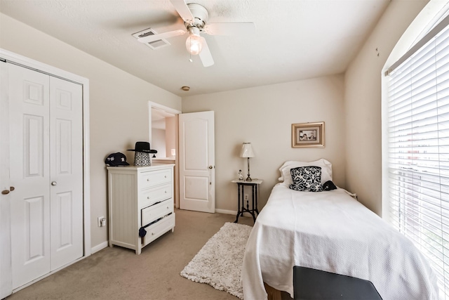 bedroom with multiple windows, light colored carpet, a closet, and a ceiling fan
