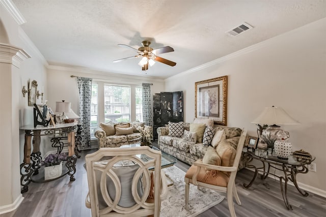 living room featuring a ceiling fan, wood finished floors, ornamental molding, baseboards, and a textured ceiling