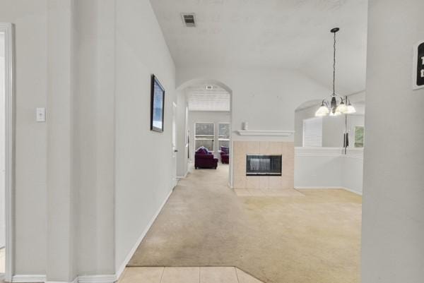 4526 Cannongate Dr, Spring Branch, TX 77373 - unfurnished living room featuring carpet, a tiled fireplace, arched walkways, vaulted ceiling, and a chandelier
