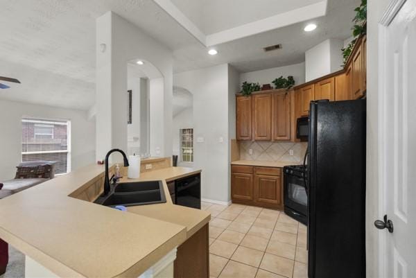 4526 Cannongate Dr, Spring Branch, TX 77373 - kitchen featuring black appliances, backsplash, a peninsula, brown cabinets, and light countertops