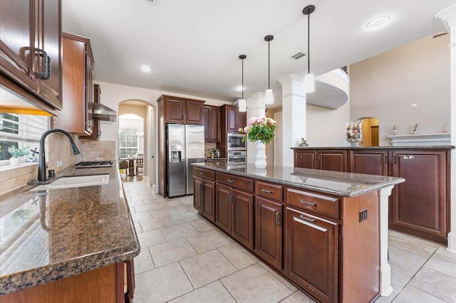 31183 Pecan Creek Dr, Brookshire, TX 77423 - kitchen featuring decorative backsplash, a center island, arched walkways, a sink, and stainless steel appliances