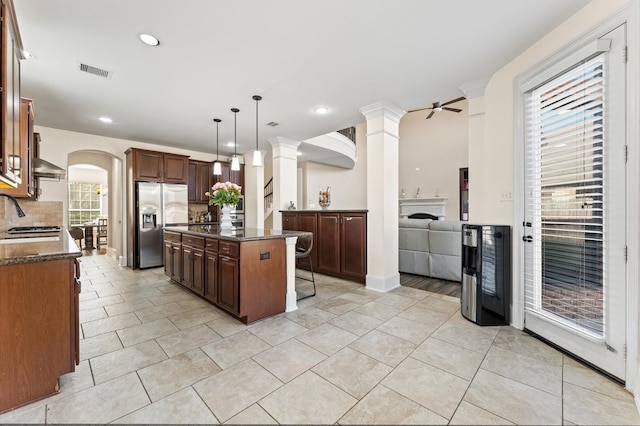 31183 Pecan Creek Dr, Brookshire, TX 77423 - kitchen with visible vents, a kitchen island, ceiling fan, stainless steel fridge with ice dispenser, and backsplash