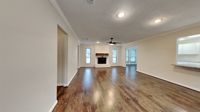 unfurnished living room featuring a textured ceiling, dark wood-style floors, ornamental molding, and baseboards