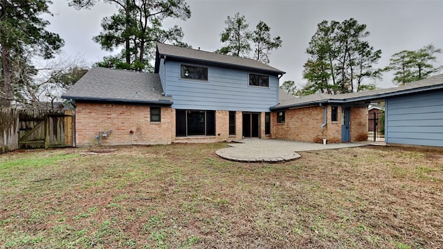 rear view of house featuring brick siding, a patio area, and a yard