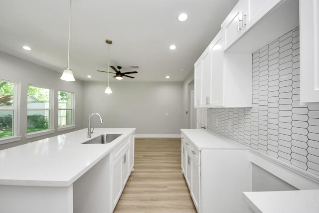kitchen featuring a ceiling fan, backsplash, light wood-type flooring, a sink, and recessed lighting