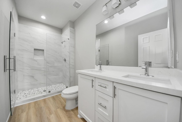 full bathroom featuring visible vents, wood finished floors, toilet, a sink, and a marble finish shower