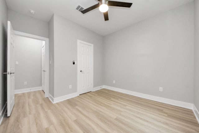 empty room with ceiling fan, visible vents, baseboards, and light wood finished floors