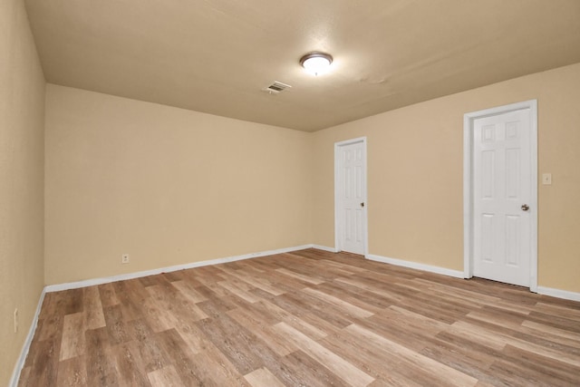 empty room featuring baseboards, light wood-type flooring, and visible vents