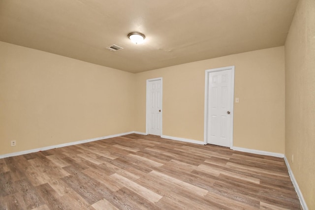 unfurnished room with baseboards, light wood-type flooring, and visible vents