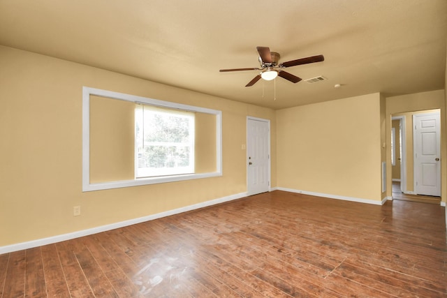 empty room featuring visible vents, a ceiling fan, baseboards, and wood finished floors