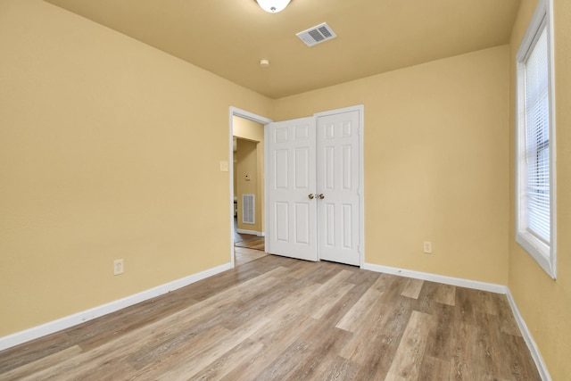 unfurnished bedroom with visible vents, baseboards, and wood finished floors