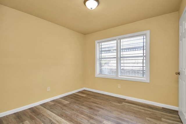 spare room featuring baseboards and wood finished floors
