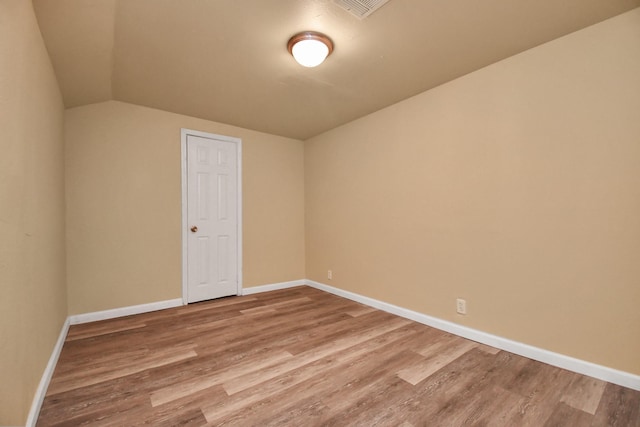 empty room with baseboards, visible vents, wood finished floors, and lofted ceiling