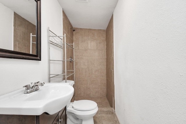 bathroom featuring tile patterned flooring, vanity, toilet, visible vents, and tiled shower
