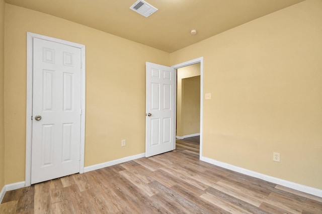 unfurnished bedroom featuring baseboards, wood finished floors, and visible vents