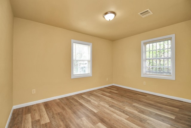 unfurnished room featuring baseboards, wood finished floors, and visible vents