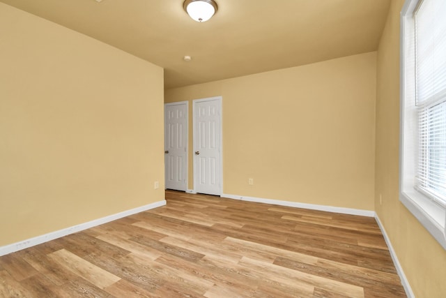 unfurnished room with baseboards and light wood finished floors