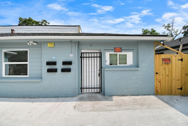 entrance to property featuring brick siding and fence