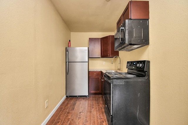 kitchen with appliances with stainless steel finishes, a sink, light countertops, dark wood finished floors, and baseboards