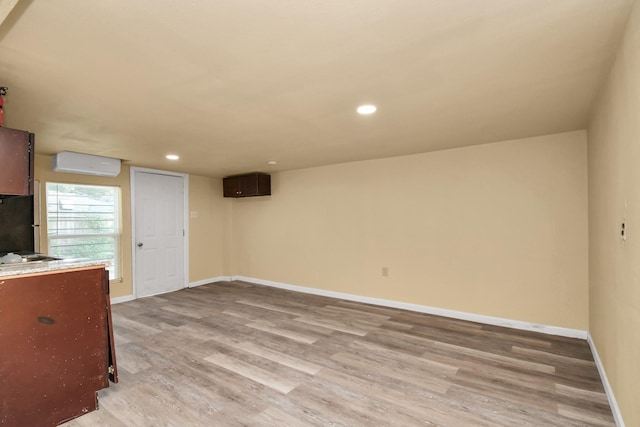 interior space featuring recessed lighting, baseboards, a wall unit AC, and light wood finished floors