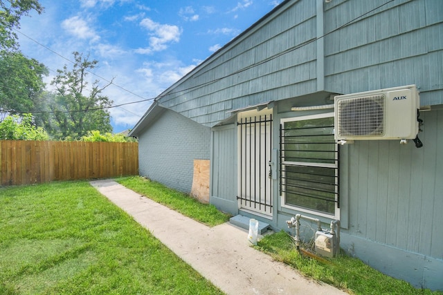view of side of property featuring fence, ac unit, a lawn, and brick siding