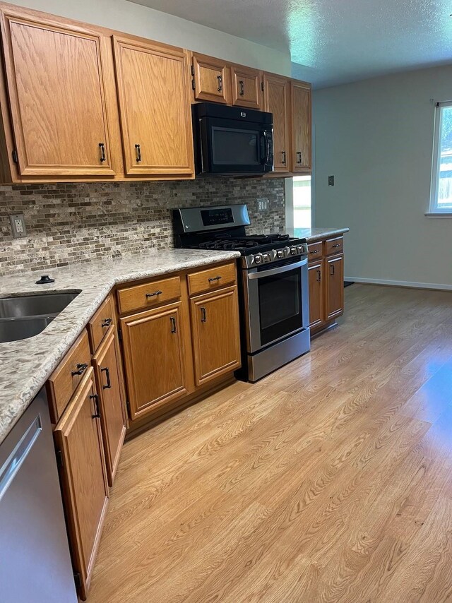 20018 Big Timber Dr, Humble, TX 77346 - kitchen with stainless steel appliances, backsplash, light wood-style floors, and brown cabinets