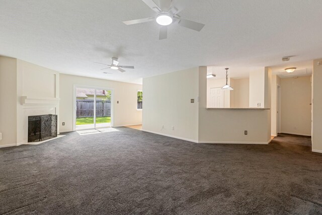 20018 Big Timber Dr, Humble, TX 77346 - unfurnished living room featuring ceiling fan, a fireplace with flush hearth, dark colored carpet, and baseboards