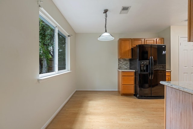 20018 Big Timber Dr, Humble, TX 77346 - kitchen featuring black fridge with ice dispenser, light wood-style flooring, tasteful backsplash, decorative light fixtures, and baseboards