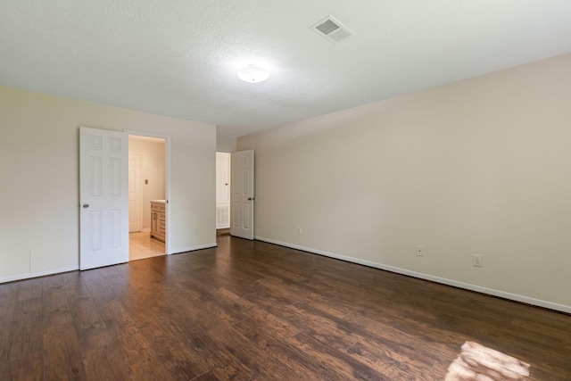 20018 Big Timber Dr, Humble, TX 77346 - unfurnished bedroom with dark wood-type flooring, baseboards, and ensuite bath
