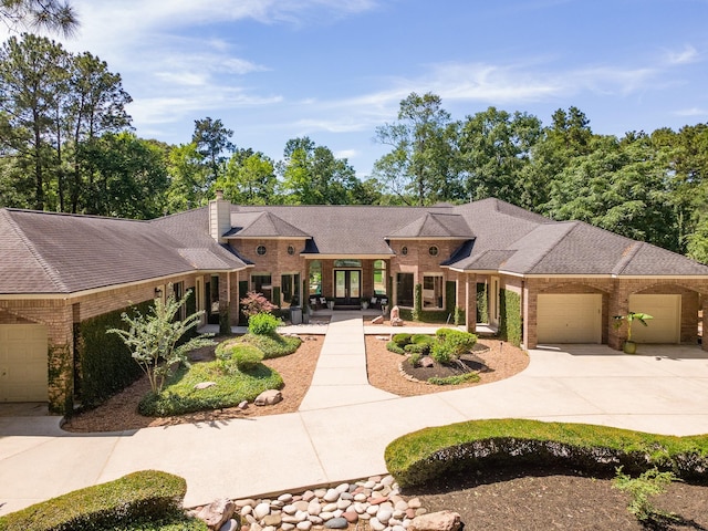 prairie-style home featuring french doors, an attached garage, driveway, and brick siding