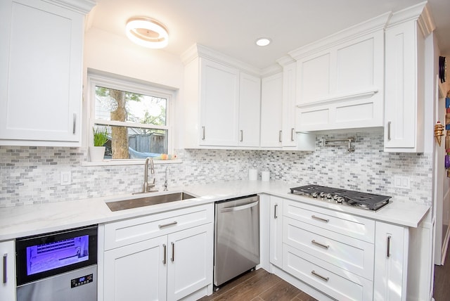 kitchen featuring dark wood-style flooring, white cabinets, a sink, appliances with stainless steel finishes, and backsplash