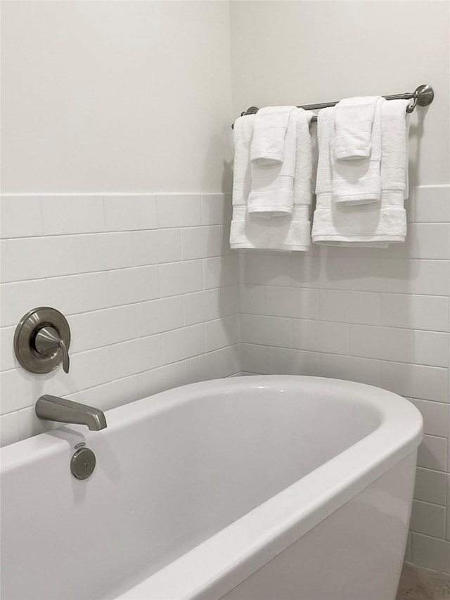 bathroom featuring tile walls, a wainscoted wall, and a bathtub