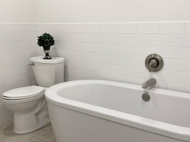 bathroom with a tub, toilet, and tile walls