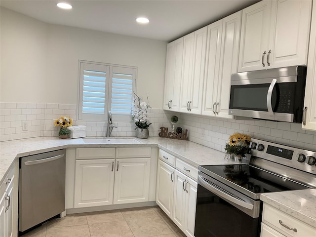 kitchen with a sink, backsplash, white cabinets, and stainless steel appliances