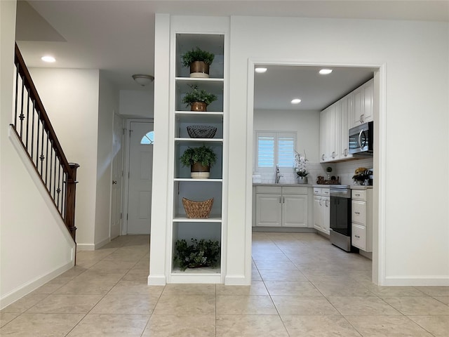 interior space with white cabinets, stainless steel appliances, recessed lighting, and a sink