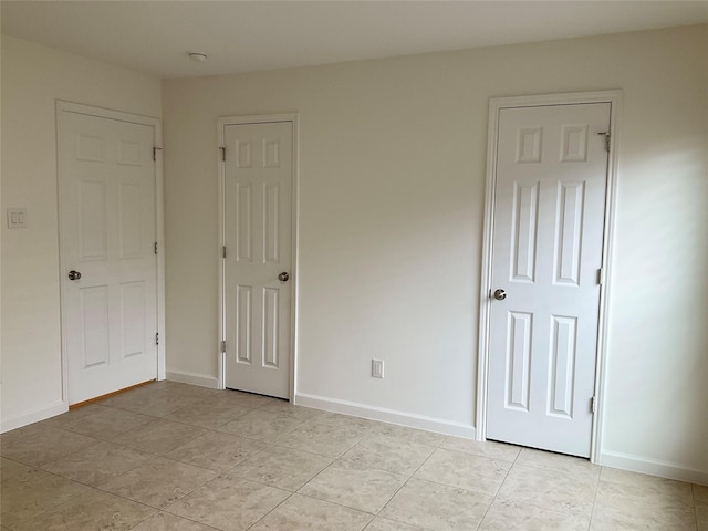 unfurnished bedroom with baseboards and light tile patterned flooring