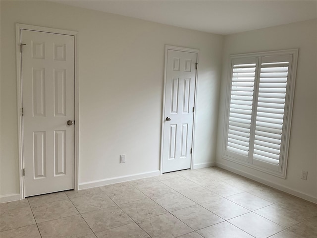 unfurnished bedroom with light tile patterned floors and baseboards