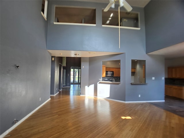 3905 Austin Lake Ct, Pearland, TX 77581 - unfurnished living room featuring a ceiling fan, baseboards, wood finished floors, and a towering ceiling
