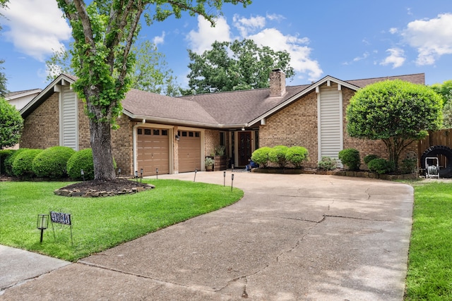 view of front of house featuring brick siding, a garage, driveway, a front lawn, and a chimney