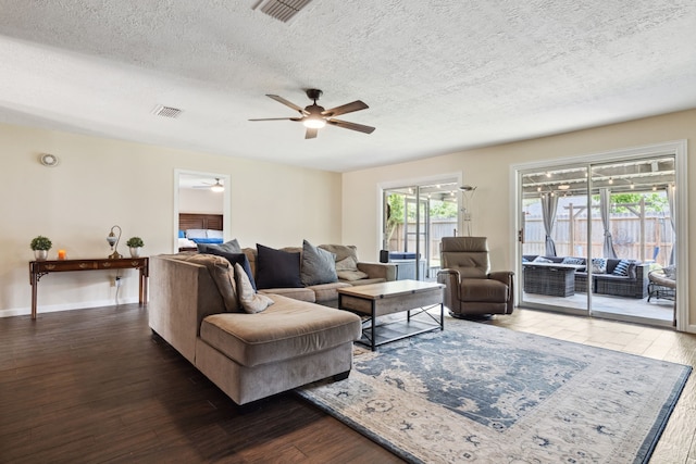 living room featuring a ceiling fan, a textured ceiling, wood finished floors, and baseboards