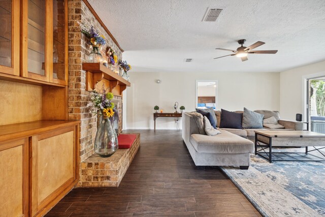 living area featuring a textured ceiling, dark wood-style flooring, ceiling fan, and baseboards