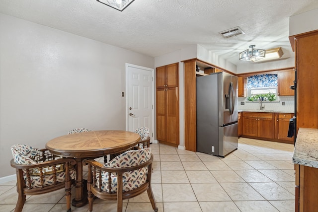 dining area with a textured ceiling and light tile patterned floors