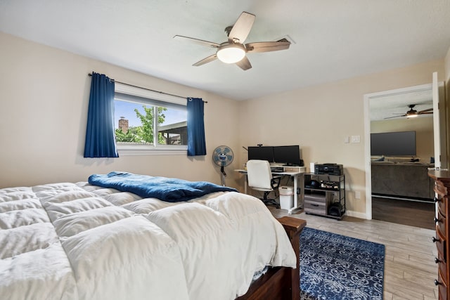 bedroom with wood finished floors, an office area, and ceiling fan