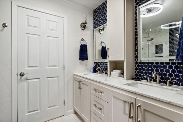 bathroom with a tile shower, backsplash, double vanity, and tile patterned flooring