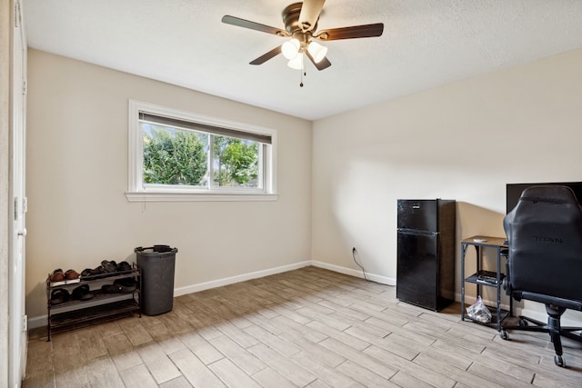 office area with light wood finished floors, a ceiling fan, and baseboards