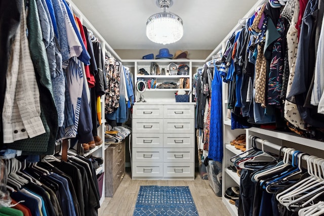 spacious closet featuring a chandelier and light wood-type flooring