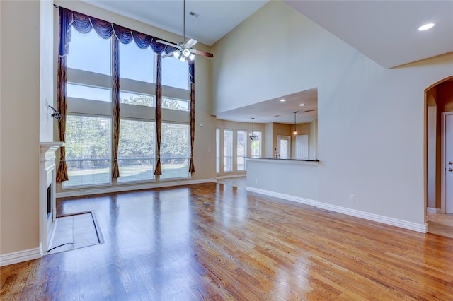 5507 Opal Cove Ct, Katy, TX 77494 - unfurnished living room featuring light wood-type flooring, arched walkways, baseboards, and a fireplace with flush hearth